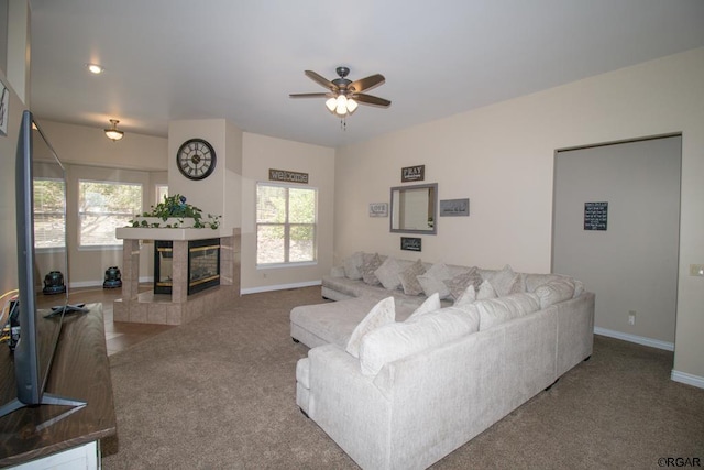 living room featuring a tiled fireplace, ceiling fan, carpet floors, and a healthy amount of sunlight