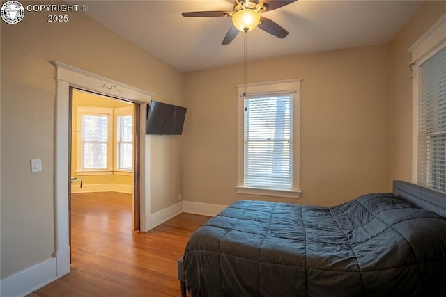 bedroom with ceiling fan, multiple windows, and light hardwood / wood-style flooring