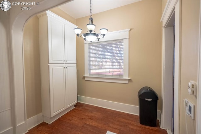 unfurnished dining area with dark hardwood / wood-style flooring and a notable chandelier