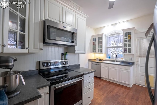 kitchen with appliances with stainless steel finishes, white cabinetry, sink, ceiling fan, and dark wood-type flooring