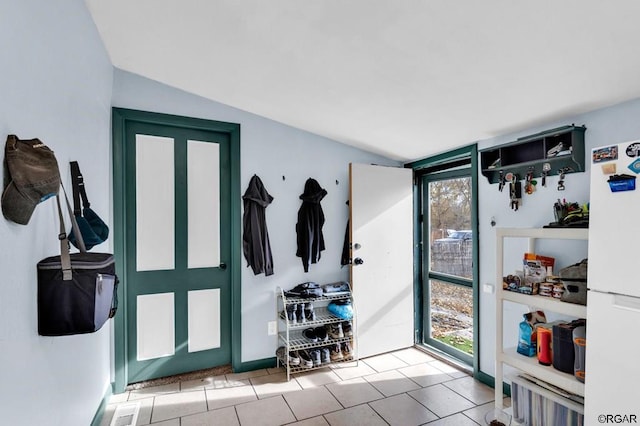 interior space with plenty of natural light, light tile patterned floors, and lofted ceiling