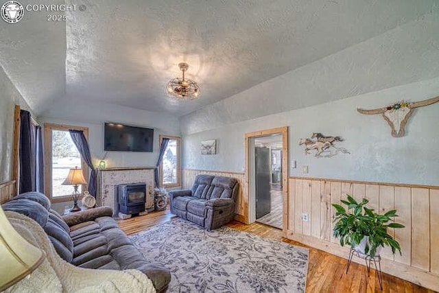 living room with wood finished floors, vaulted ceiling, a textured ceiling, and wainscoting