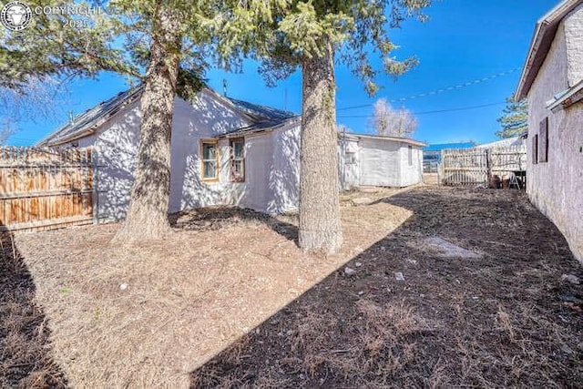 view of property exterior featuring an outdoor structure, a fenced backyard, and stucco siding