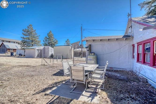 view of yard featuring outdoor dining space, a patio, and an outbuilding