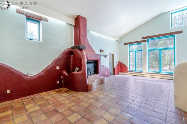 interior space with a large fireplace, baseboard heating, a healthy amount of sunlight, and vaulted ceiling