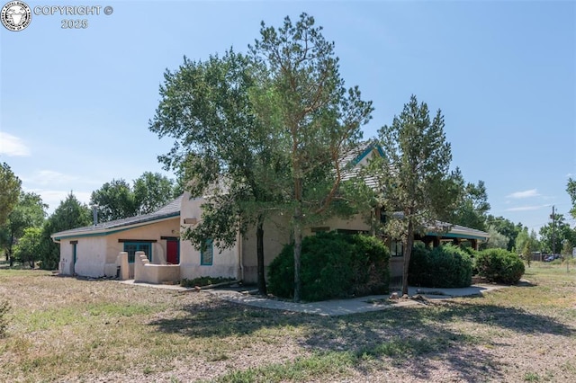 view of side of home with stucco siding and a yard