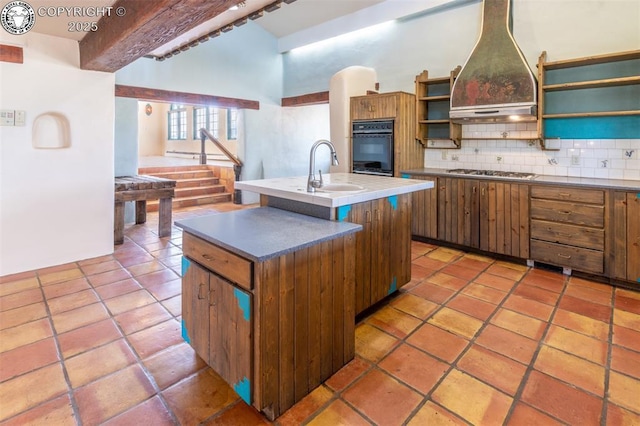 kitchen with a sink, open shelves, tasteful backsplash, custom exhaust hood, and stainless steel gas cooktop