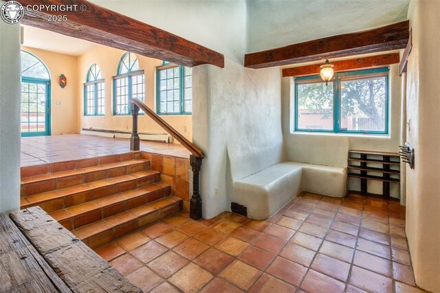 interior space featuring a baseboard radiator, beam ceiling, and a healthy amount of sunlight