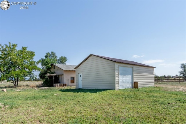 back of house featuring an outdoor structure, a lawn, and a garage