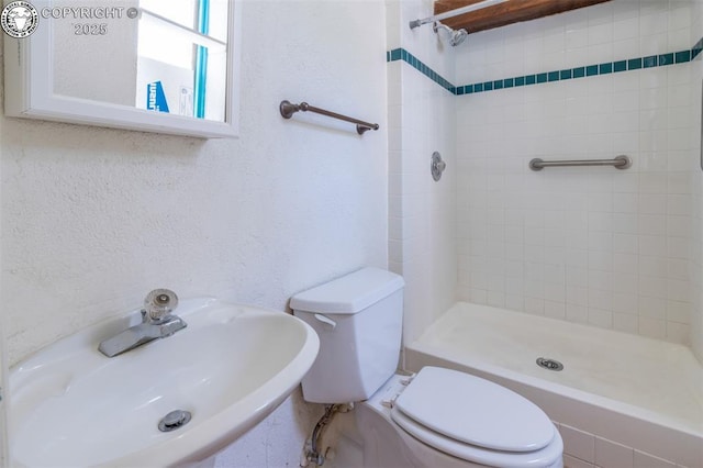 full bathroom featuring a shower stall, toilet, a textured wall, and a sink