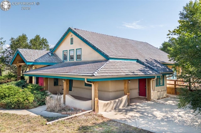 view of front of property featuring stucco siding, a tile roof, and fence