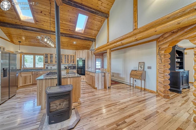 kitchen with a wood stove, wooden ceiling, light wood finished floors, high vaulted ceiling, and a skylight
