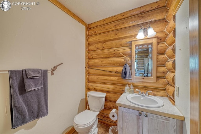bathroom with toilet, wood finished floors, vanity, and log walls