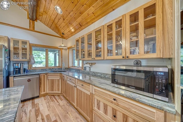 kitchen featuring glass insert cabinets, a sink, stainless steel appliances, light stone countertops, and vaulted ceiling