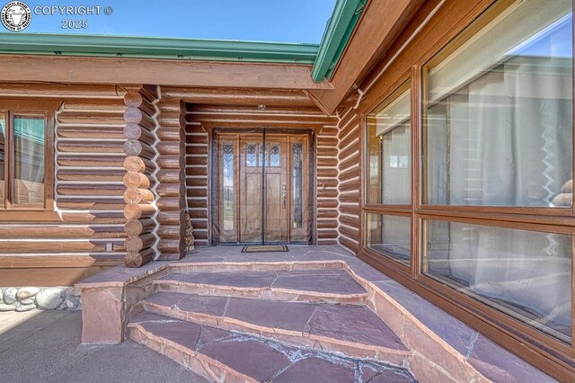 view of exterior entry featuring log siding