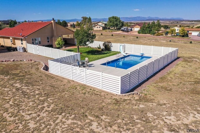 view of swimming pool with a water slide, a yard, a mountain view, and a patio area