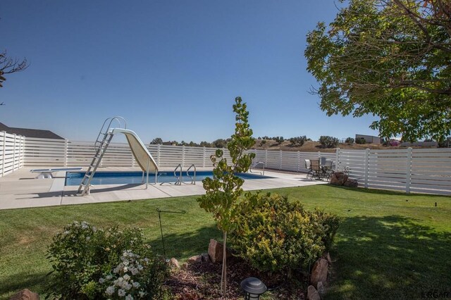 view of pool featuring a yard, a patio area, and a water slide