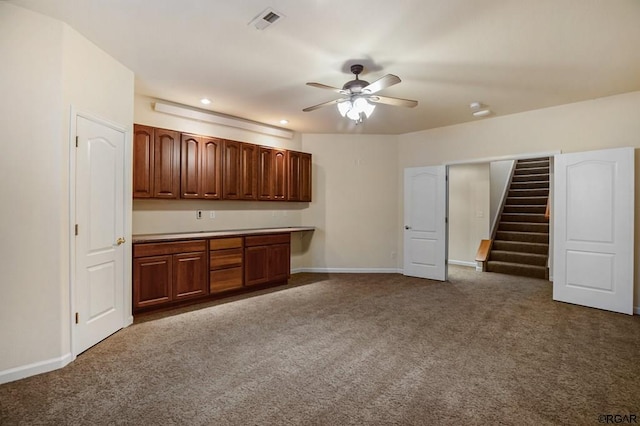 kitchen with ceiling fan and dark colored carpet