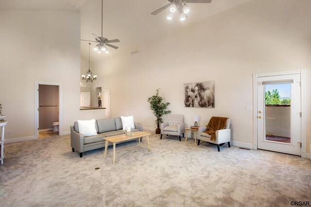 carpeted living room with ceiling fan with notable chandelier and high vaulted ceiling