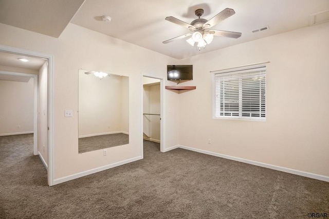 unfurnished bedroom with ceiling fan and dark colored carpet