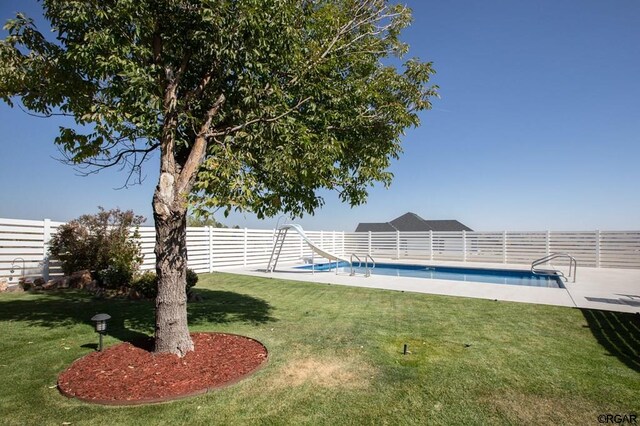 view of pool with a patio area, a lawn, and a water slide