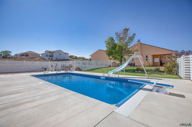 view of swimming pool featuring a water slide, a diving board, and a patio area