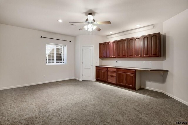 kitchen featuring ceiling fan, built in desk, and dark carpet