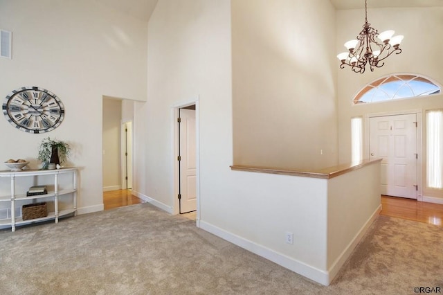 carpeted foyer entrance with a towering ceiling, a chandelier, and a wealth of natural light