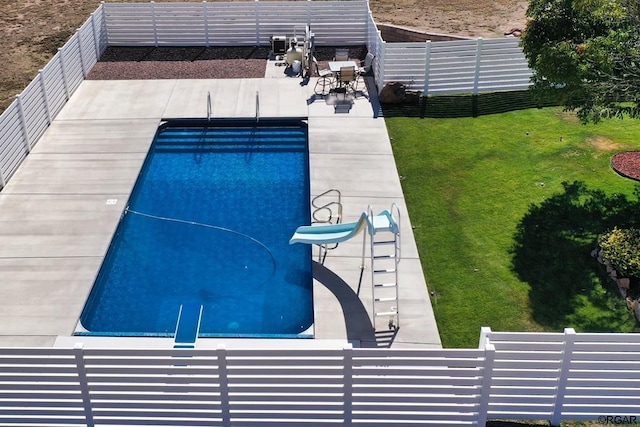 view of swimming pool featuring a patio, a water slide, and a lawn