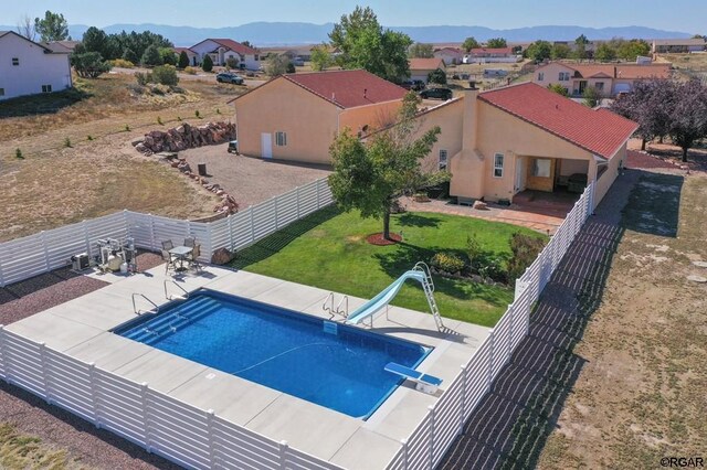 view of swimming pool featuring a water slide, a diving board, a patio area, and a mountain view