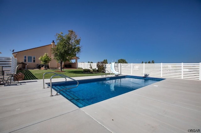 view of pool featuring a water slide, a lawn, a diving board, and a patio area