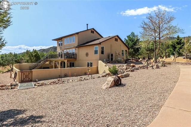 back of house with stairway, fence, and stucco siding