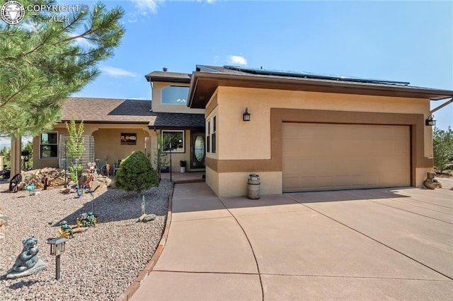 view of front facade with stucco siding, a garage, solar panels, and driveway