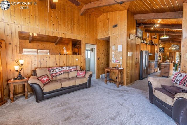 carpeted living room featuring wooden walls, wooden ceiling, lofted ceiling with beams, and ceiling fan