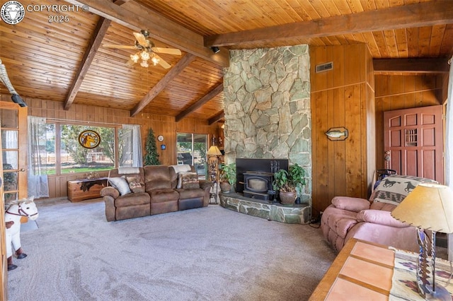 carpeted living room with wood walls, wood ceiling, high vaulted ceiling, a wood stove, and beamed ceiling