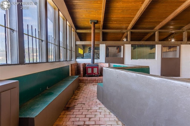 unfurnished sunroom with a wood stove and wooden ceiling