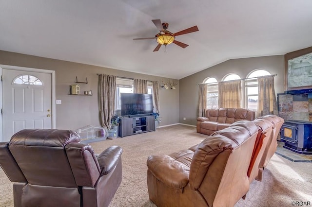 carpeted living room featuring vaulted ceiling, a wood stove, and ceiling fan