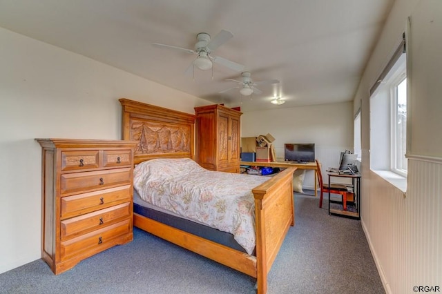 bedroom featuring ceiling fan, wooden walls, and dark carpet