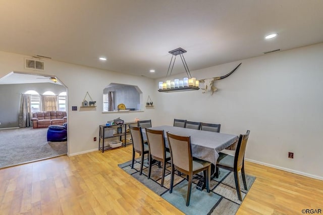 dining area with ceiling fan with notable chandelier and light hardwood / wood-style floors