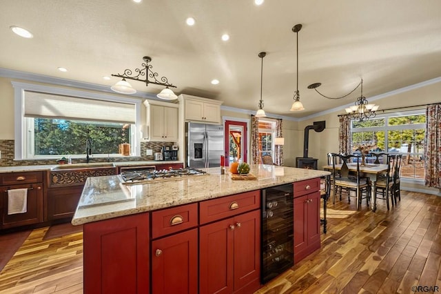 kitchen featuring a kitchen island, appliances with stainless steel finishes, pendant lighting, wine cooler, and crown molding