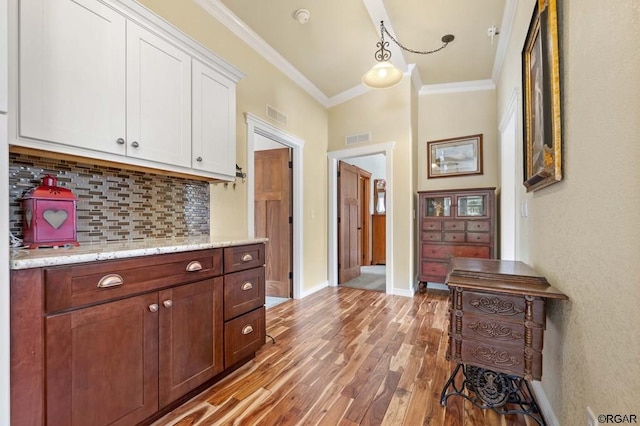 interior space featuring crown molding, light hardwood / wood-style flooring, white cabinetry, light stone counters, and tasteful backsplash