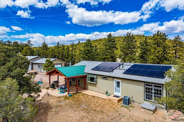 back of property featuring solar panels, central AC unit, and a patio area