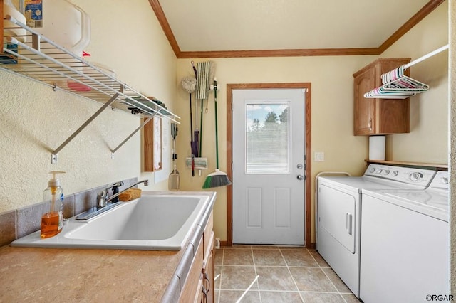 washroom featuring light tile patterned flooring, sink, cabinets, ornamental molding, and washer and clothes dryer