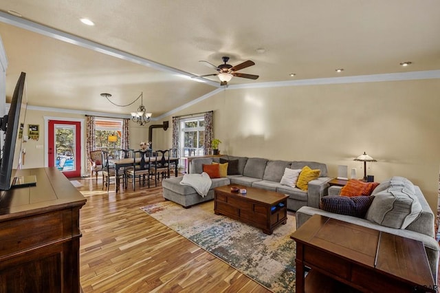 living room with ceiling fan with notable chandelier, vaulted ceiling, ornamental molding, and light hardwood / wood-style floors