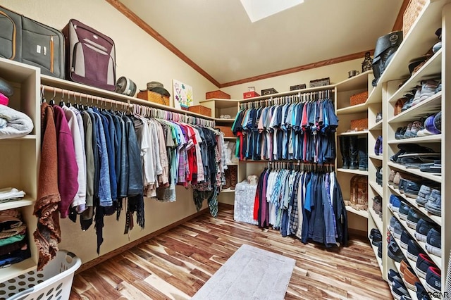 walk in closet with lofted ceiling with skylight and wood-type flooring