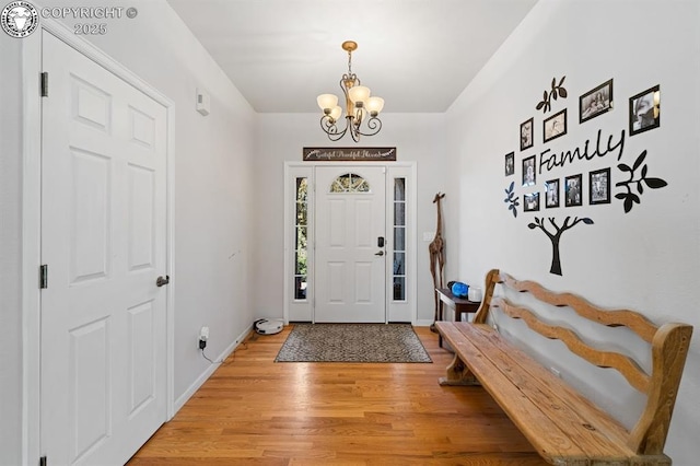 foyer entrance featuring an inviting chandelier, baseboards, and light wood-style floors