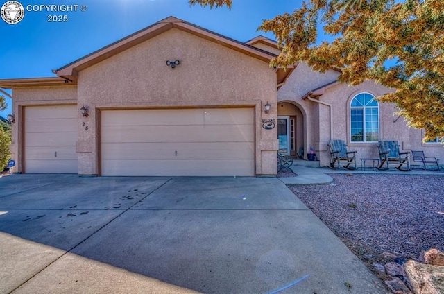 view of front of house featuring stucco siding, an attached garage, and driveway