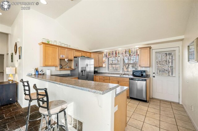 kitchen featuring lofted ceiling, sink, a kitchen bar, kitchen peninsula, and stainless steel appliances