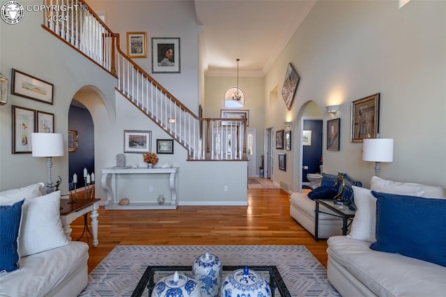 living room with a high ceiling, ornamental molding, and hardwood / wood-style floors