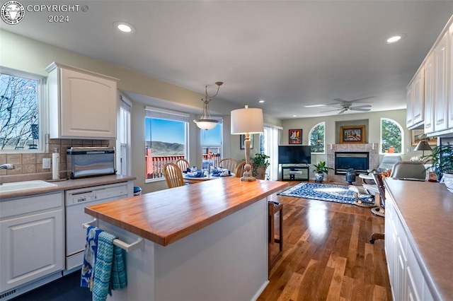 kitchen with hanging light fixtures, dishwasher, white cabinets, and wood counters